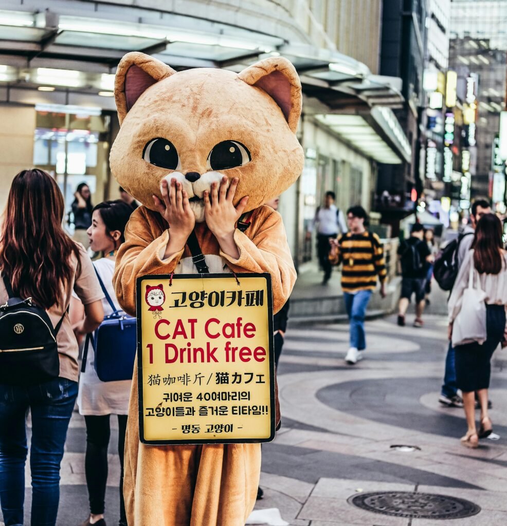 Cat mascot promoting a cat cafe on a bustling city street, engaging with pedestrians.