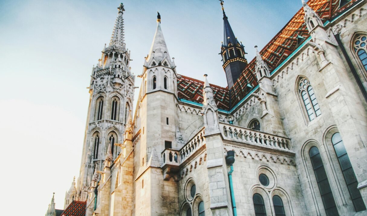 Captivating low angle view of Matthias Church in Budapest, showcasing gothic architecture against a clear sky.